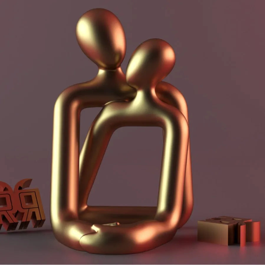 Modern minimalist loving couple resin statue in milky white or gold finish on a desk.