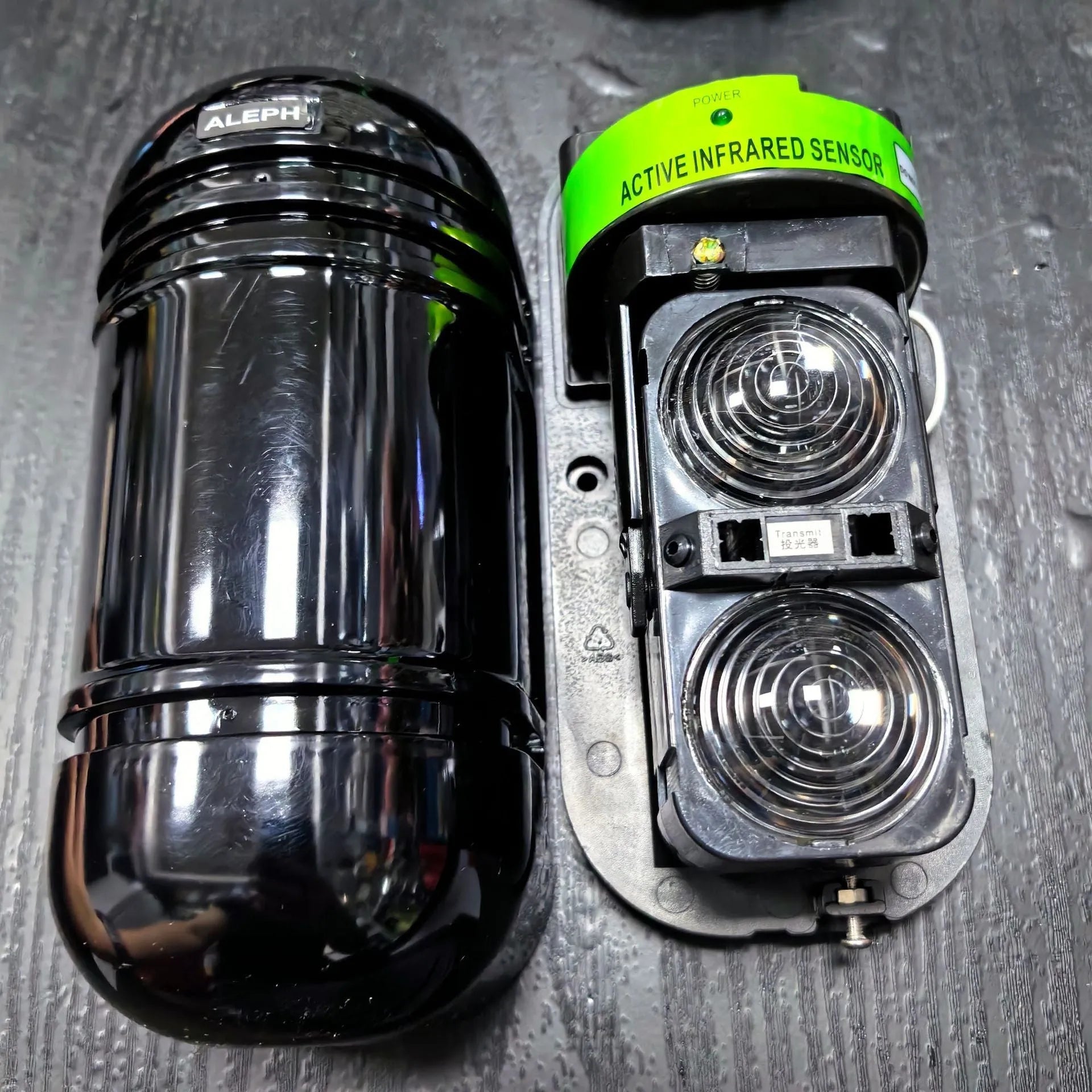 A pair of black infrared beam detectors for long-range perimeter security alarm systems.