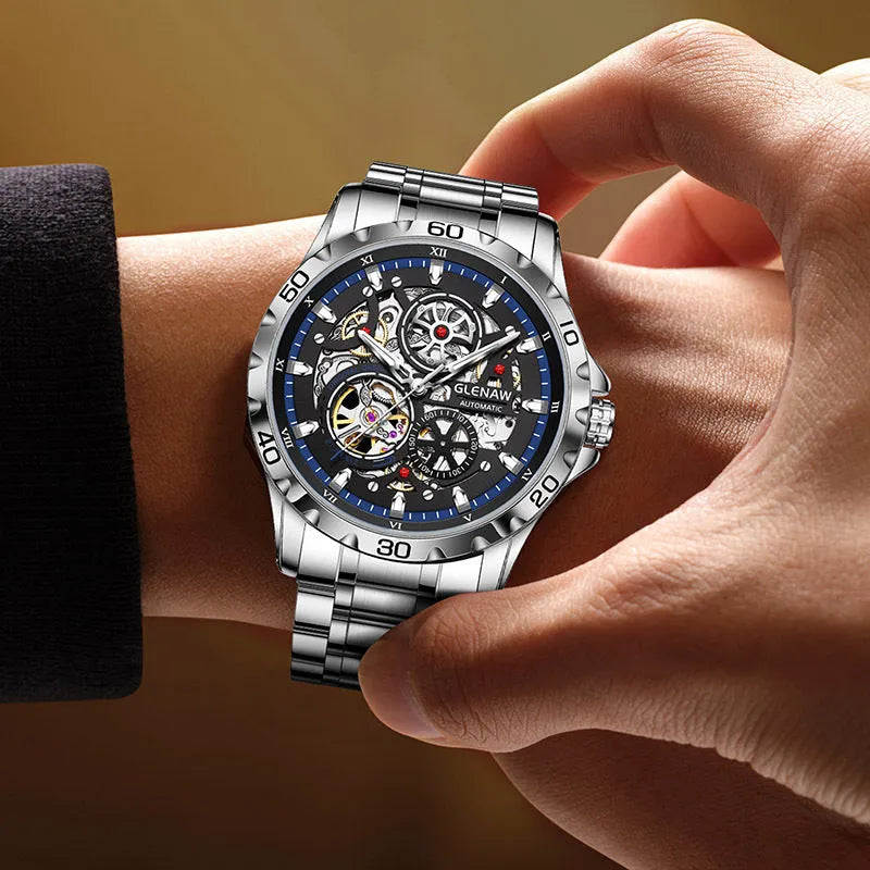 Silver men's automatic watch with hollow-out dial, luminous hands, and stainless steel strap.