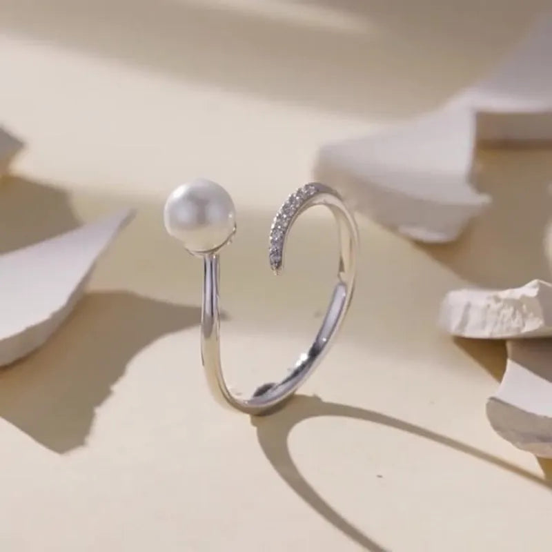 Women's adjustable sterling silver ring with a natural shell pearl on an opening loop band.