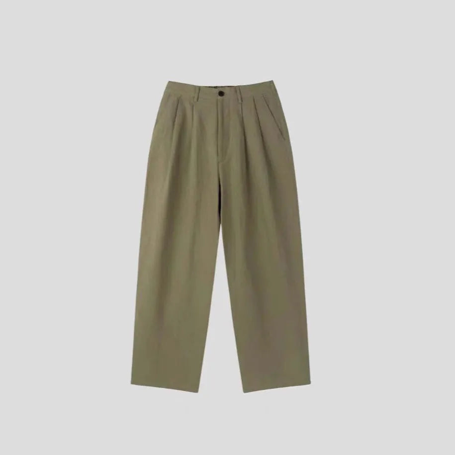 Men's apricot coloured loose-fit cotton linen trousers with a pencil leg and elastic waist on a neutral background.