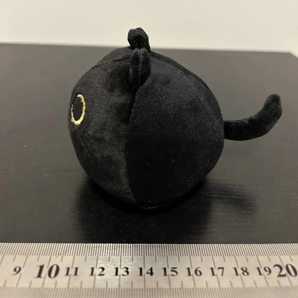Fluffy black cat plush toy with embroidered face on a soft cushion