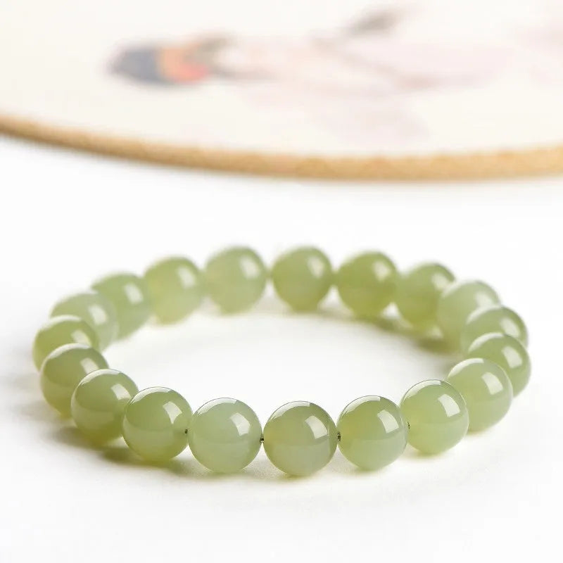 Polished Hetian jade ball bracelet in ice clear colour on a wrist, showing spherical beads.