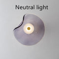 Round glass wall lamp in cognac colour mounted beside bed with warm lighting