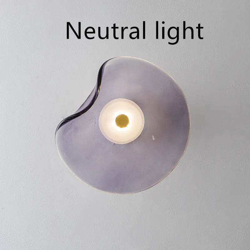 Round glass wall lamp in cognac colour mounted beside bed with warm lighting