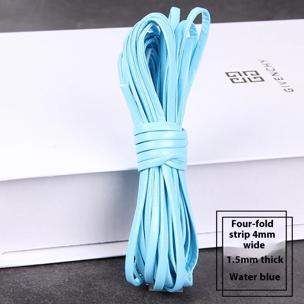 Spool of braided PU leather craft cord in beige, showing texture and width next to scissors on a craft table.