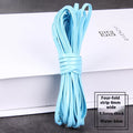 Spool of braided PU leather craft cord in beige, showing texture and width next to scissors on a craft table.