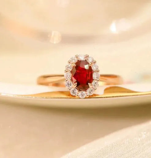 Women's silver ring with gold pigeon and red gemstone floral inlay on a finger.