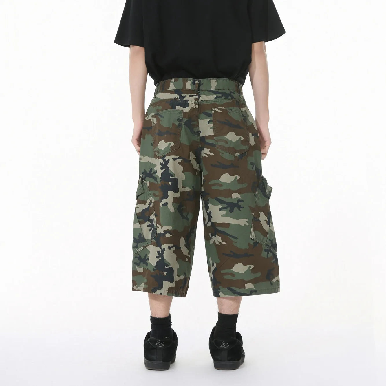 Men's green camouflage cotton trousers with wide loose legs, large side pockets, and cropped length