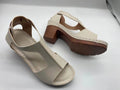 Women's white peep toe wedge sandals with a buckle and low heel on a neutral background.