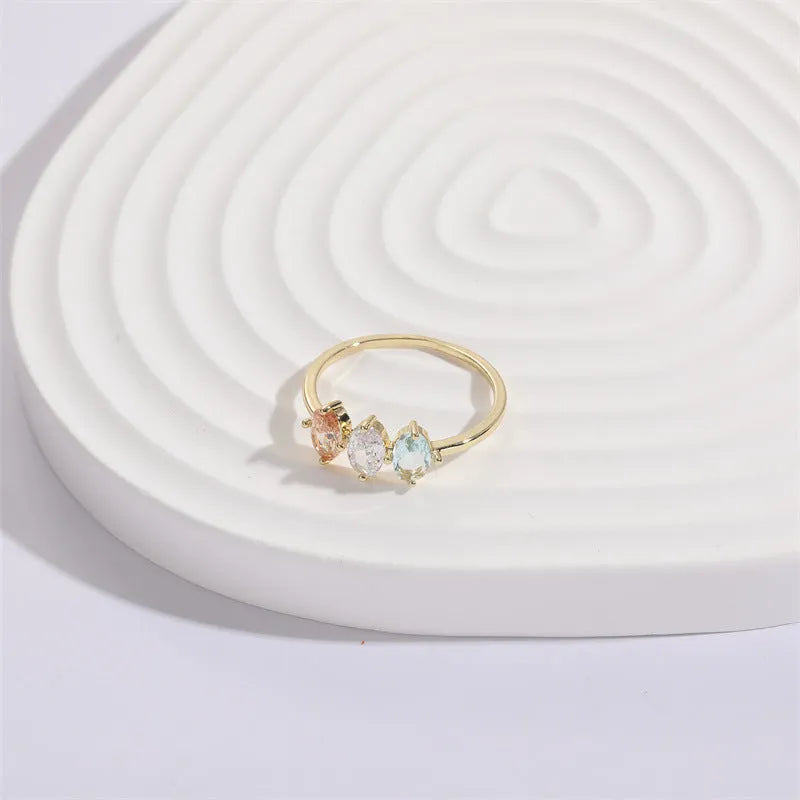 Geometric triangle birthstone ring with tricolour zircon and horse eye motif in gold plating.