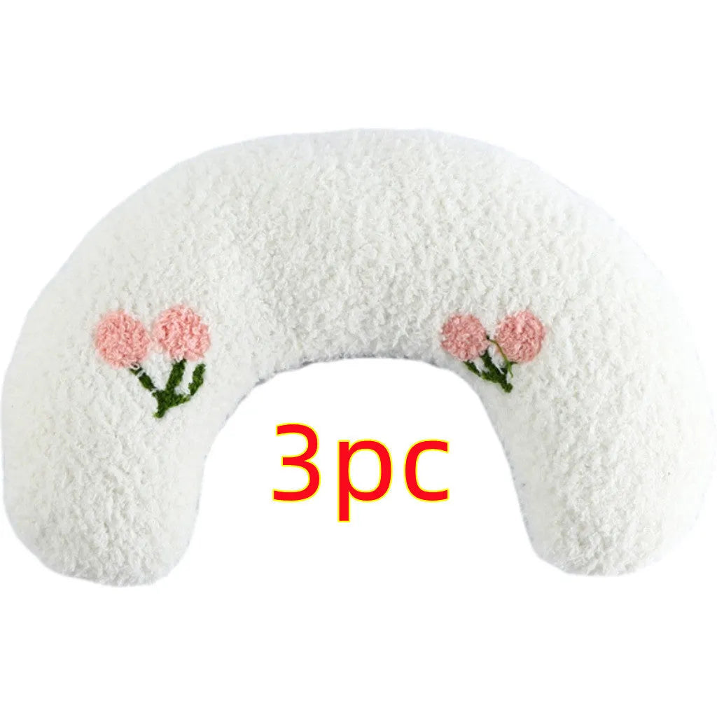 Small white blue yellow U-shaped plush pillow for cats and small dogs on a bed.