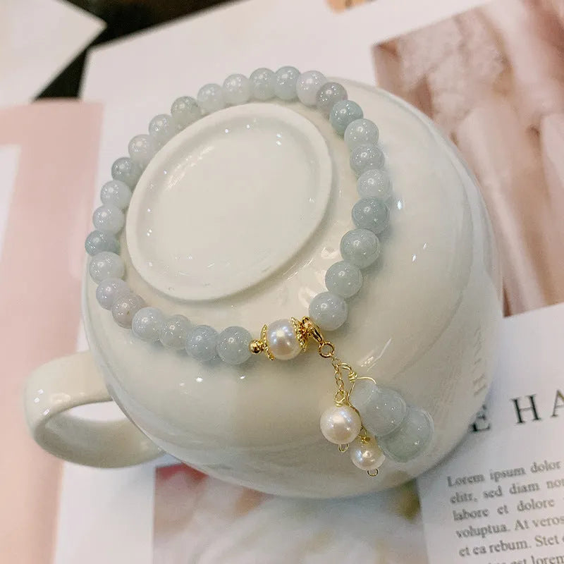 Close-up of a women's jade bracelet with a gourd motif, emerald jade insets, and pearl accents.