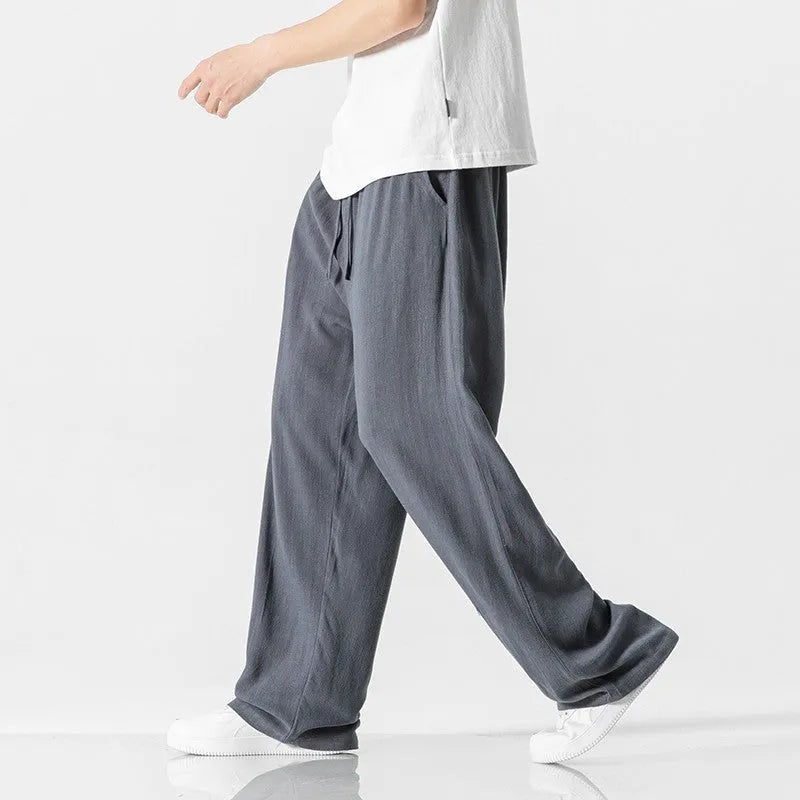 Men's beige loose-fit linen-style bamboo fibre trousers with a cropped leg and drawstring waist laid flat.