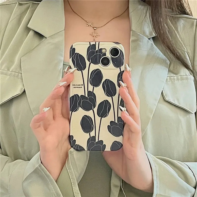 Black silicone iPhone case with a tulip pattern, shown on the back of a mobile phone.