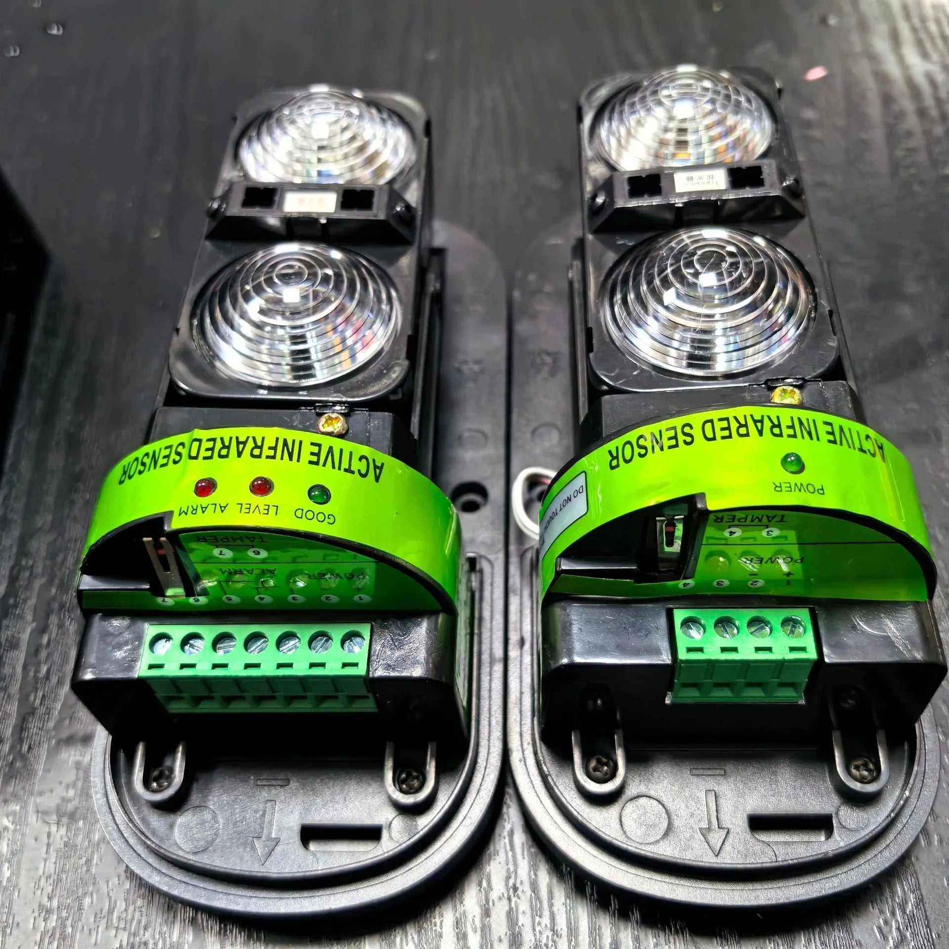 A pair of black infrared beam detectors for long-range perimeter security alarm systems.