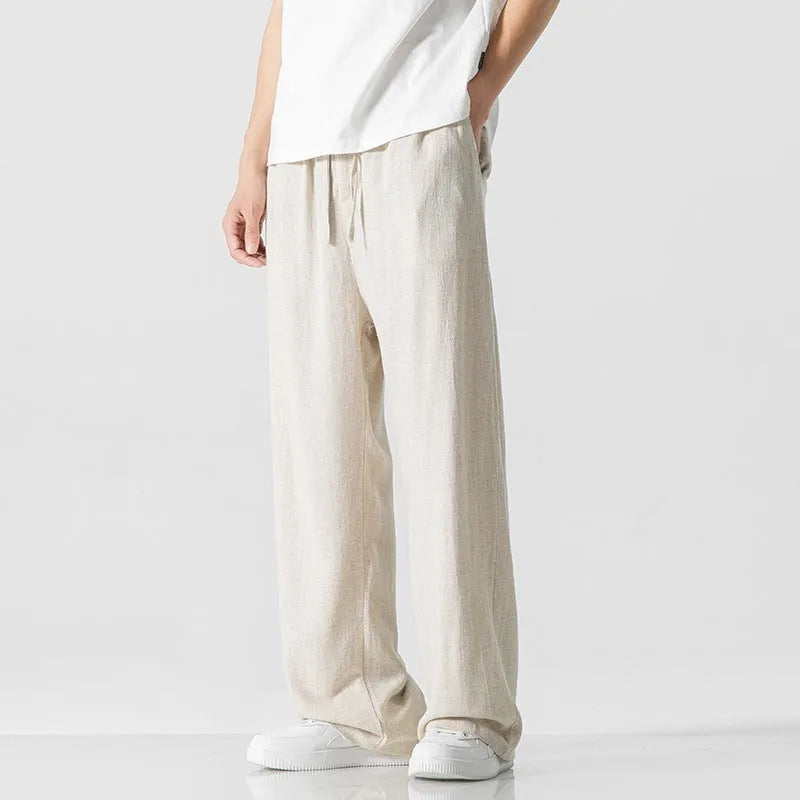 Men's beige loose-fit linen-style bamboo fibre trousers with a cropped leg and drawstring waist laid flat.