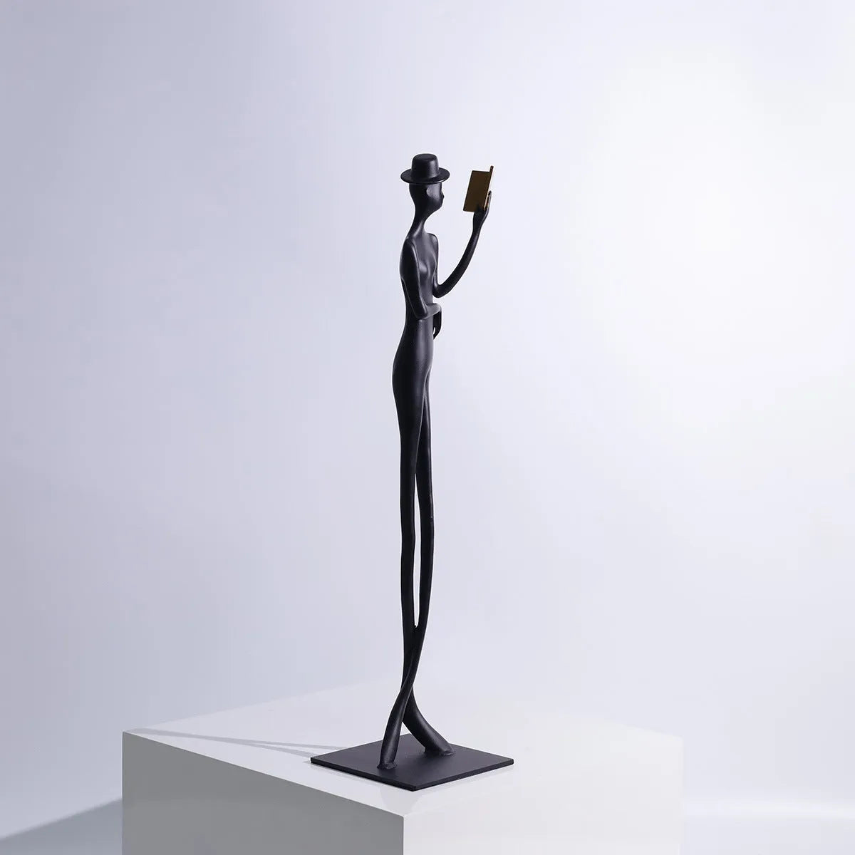 Black aluminium desktop sculpture of a woman reading, modern style.