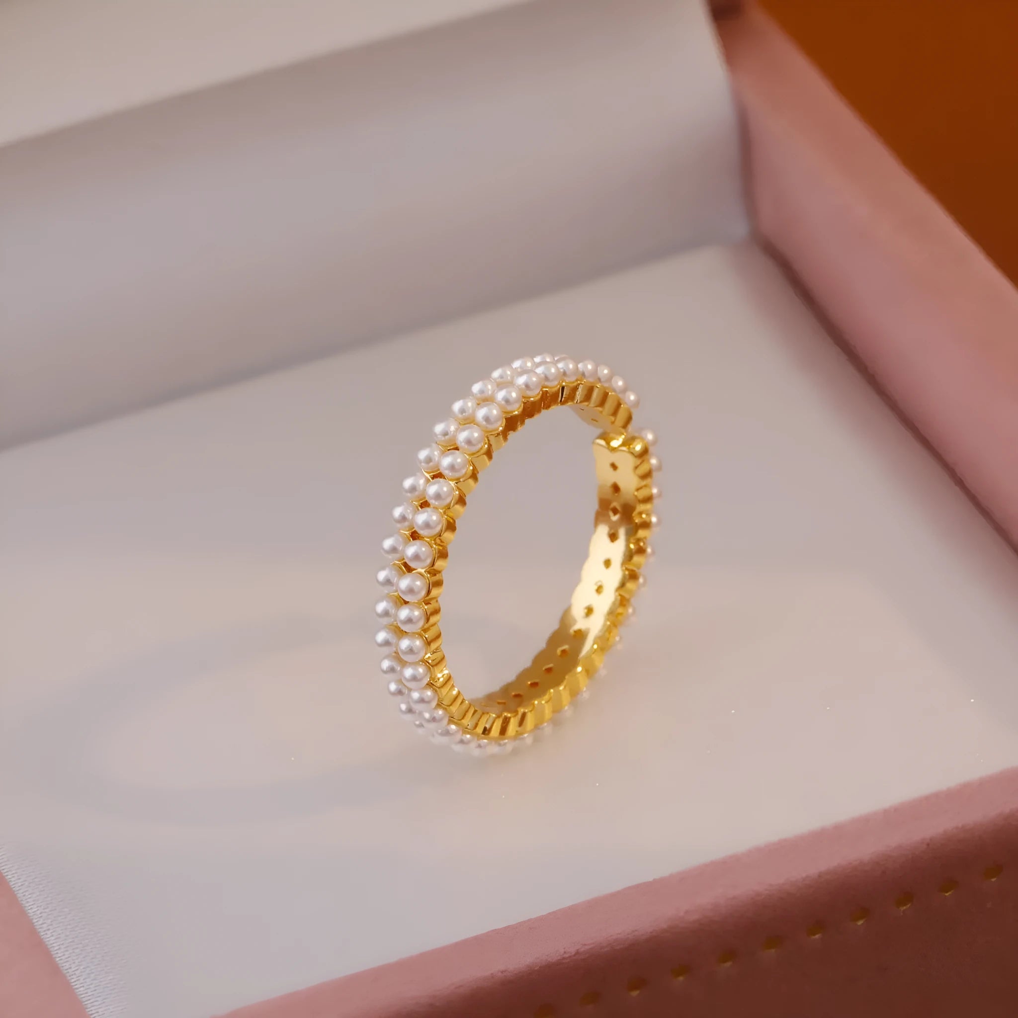 Gold geometric open ring for women with a pearl centre on a white background.