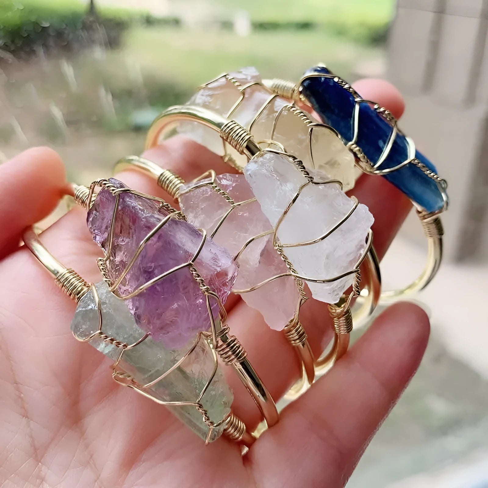 Natural rough crystal bracelet with gold geometric winding on a wrist, showing bohemian style.