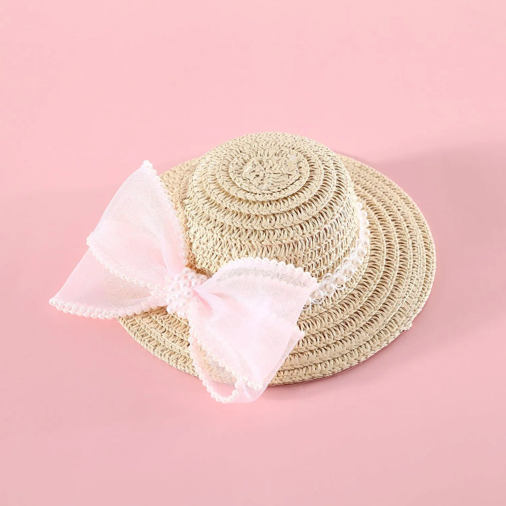 Cat wearing a woven straw hat with a pearl butterfly bow on its head.