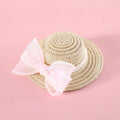 Cat wearing a woven straw hat with a pearl butterfly bow on its head.