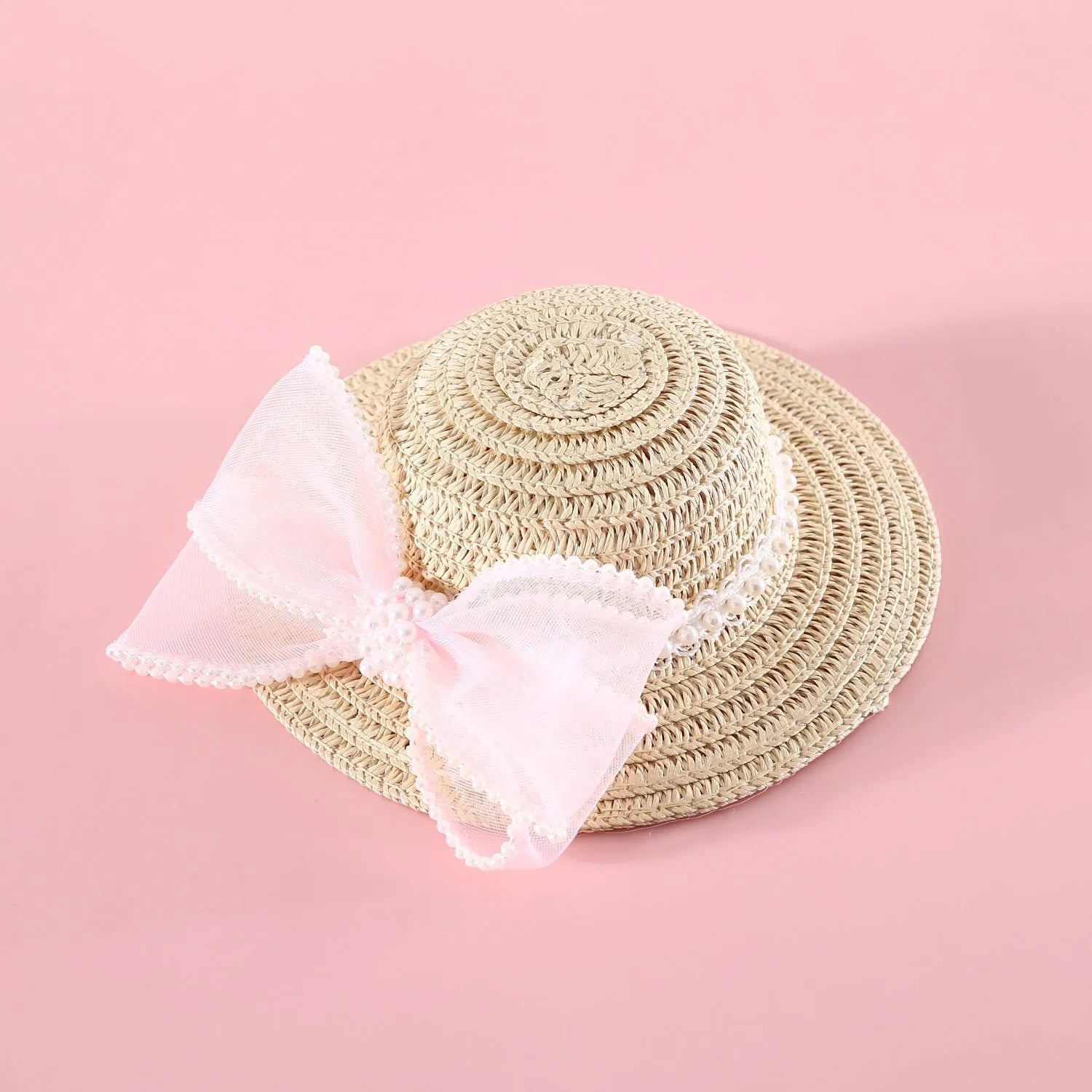 Cat wearing a woven straw hat with a pearl butterfly bow on its head.