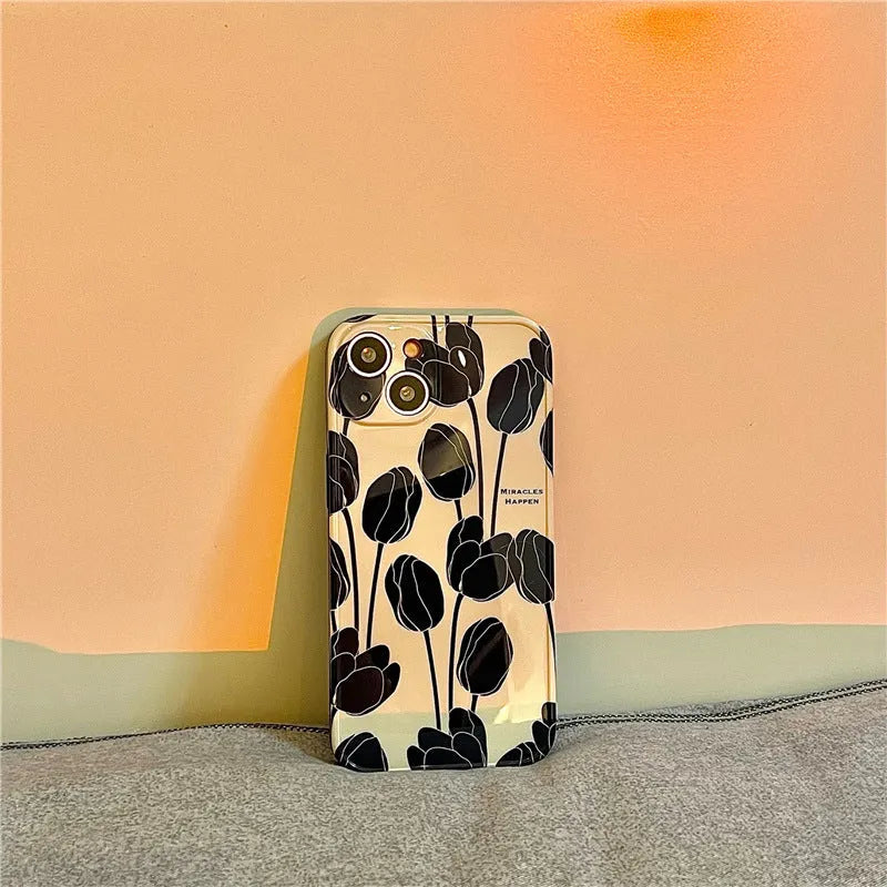 Black silicone iPhone case with a tulip pattern, shown on the back of a mobile phone.