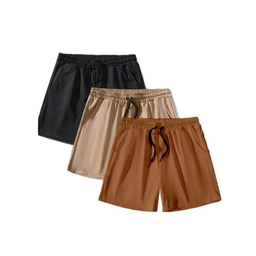 Three pairs of solid colour men's drawstring shorts in black, khaki, and light brown laid flat.