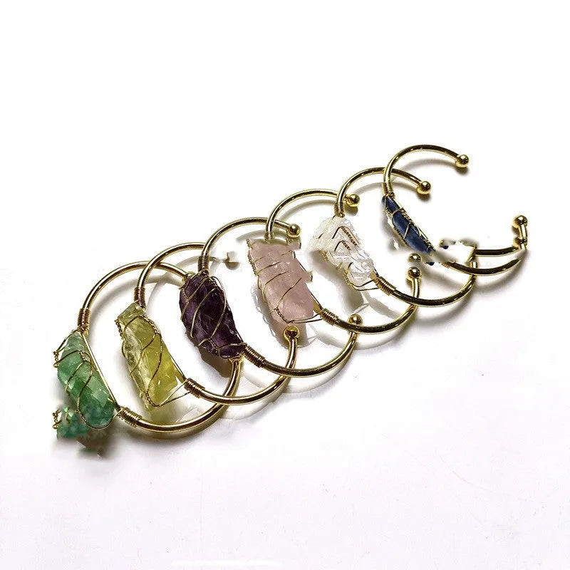 Natural rough crystal bracelet with gold geometric winding on a wrist, showing bohemian style.