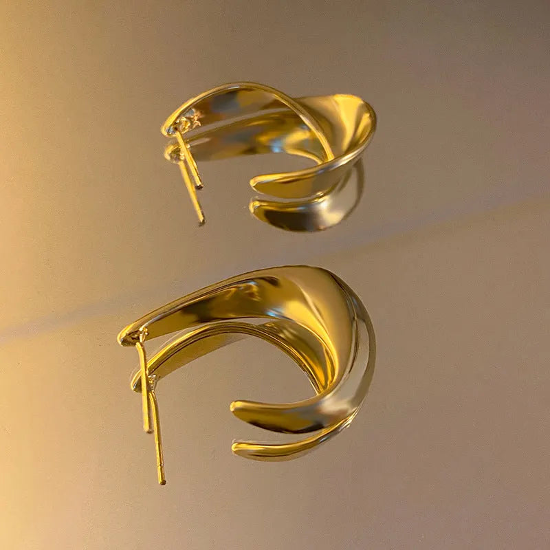 Twisted geometric metal earrings with electroplated gold or silver finish and round shape