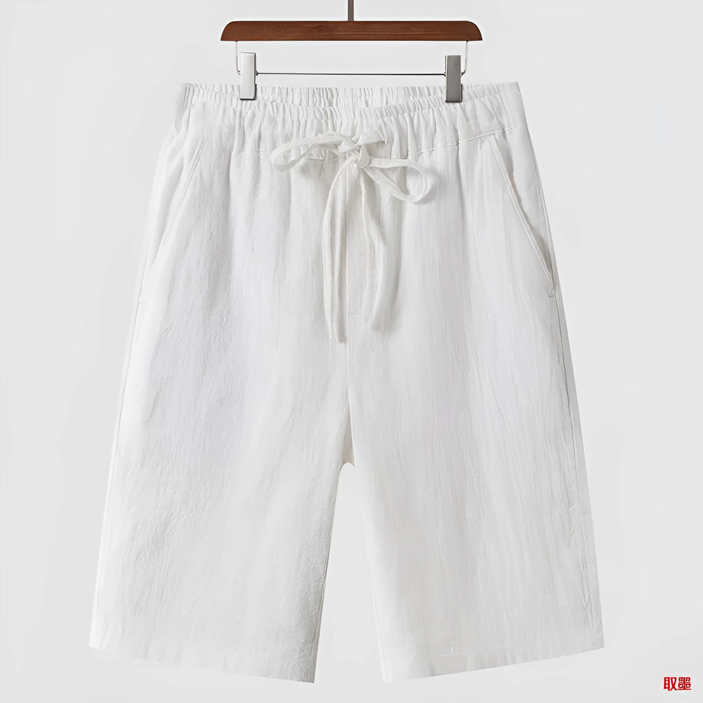 Man wearing beige linen casual shorts with a loose, cropped fit and elasticated mid waist.