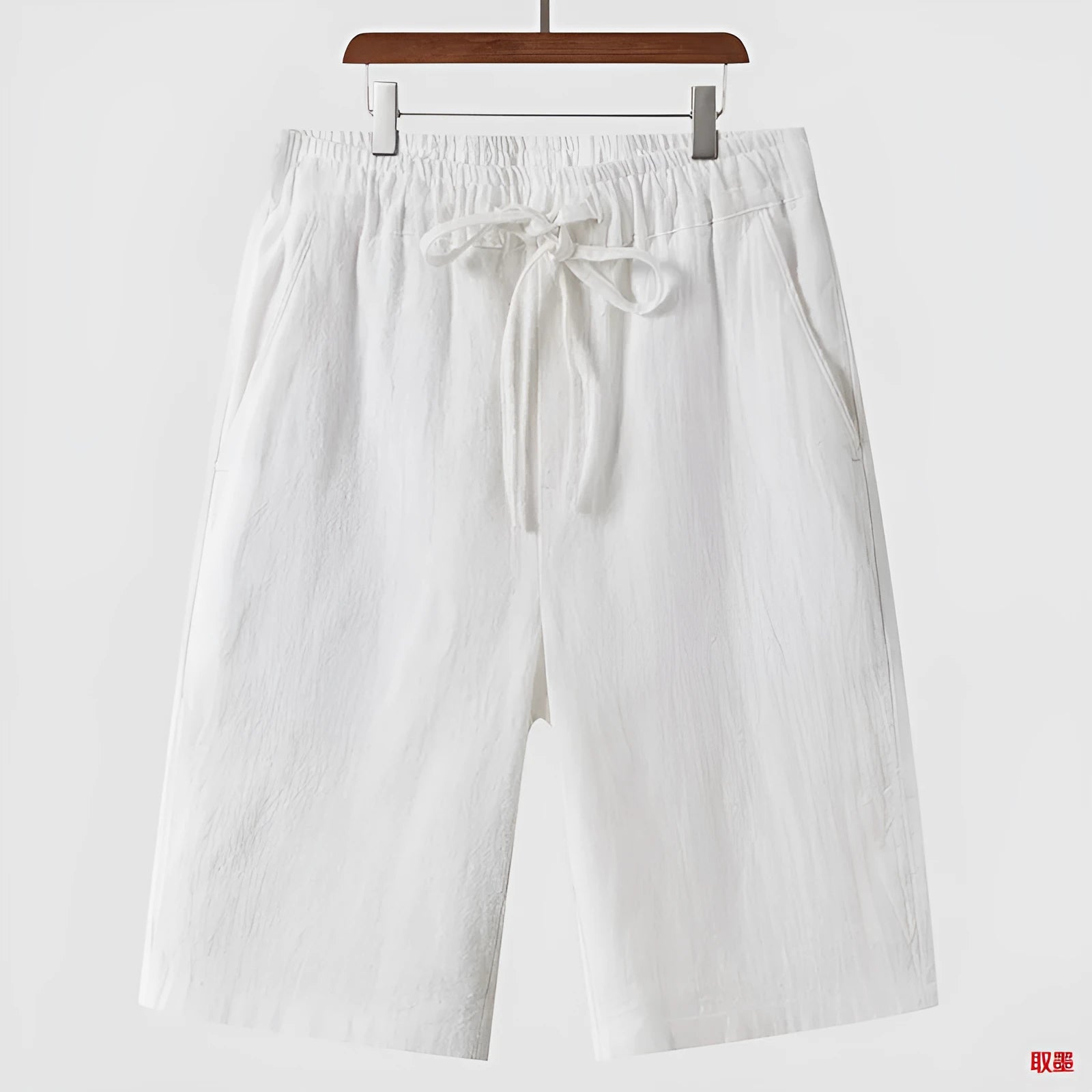 Man wearing beige linen casual shorts with a loose, cropped fit and elasticated mid waist.