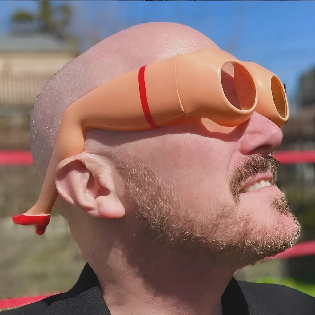 Orange plastic novelty sunglasses with a leg and hip design on the frame
