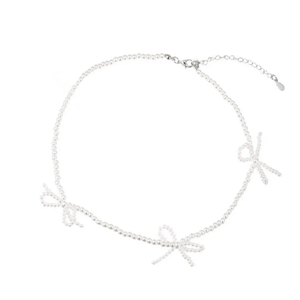White imitation pearl necklace with a geometric bow charm on an adjustable chain.