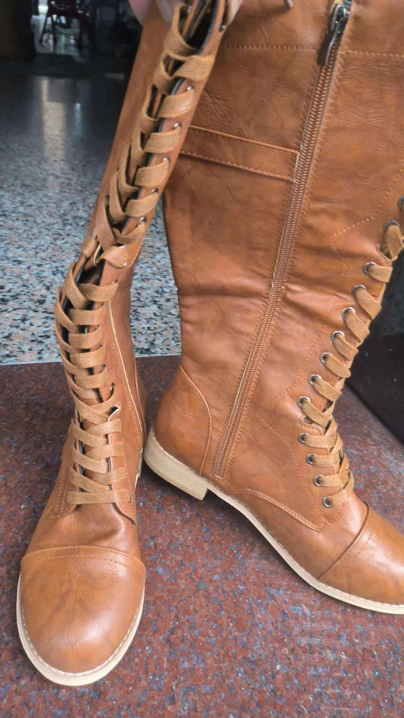 Women's black artificial PU knight boots with cross strap detail on ankle.