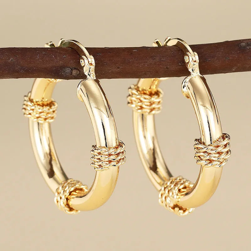 Golden geometric earrings with ring and line design elements on copper