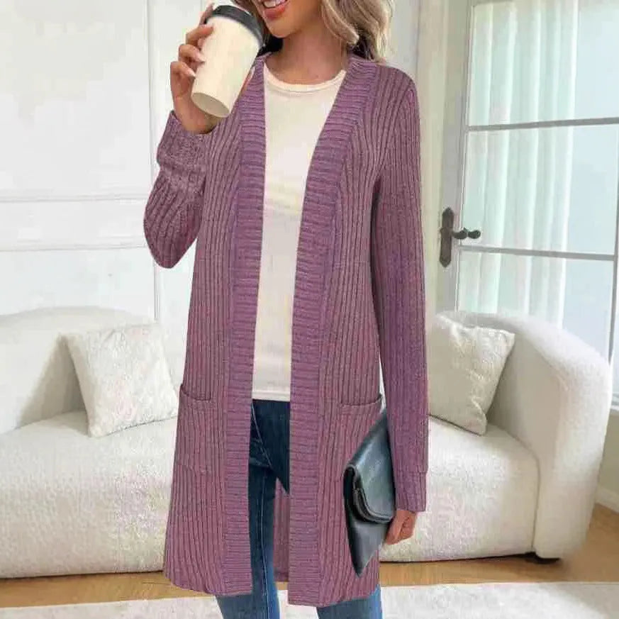 Woman wearing a loose fit, long sleeve, grey knitted cardigan jacket with patch pockets.