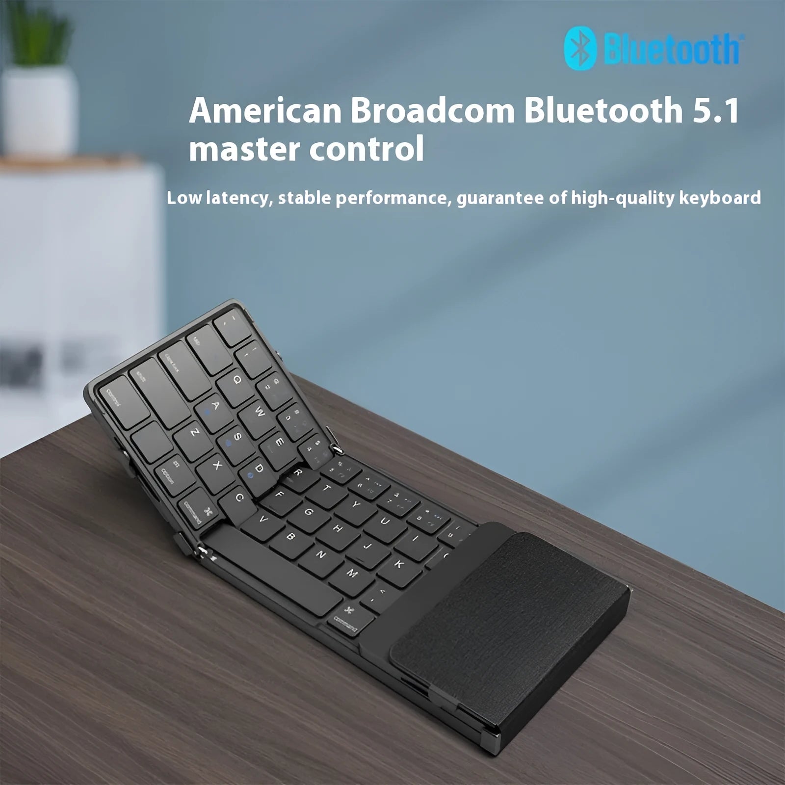 Black folding Bluetooth keyboard with touchpad unfolded next to mobile phone