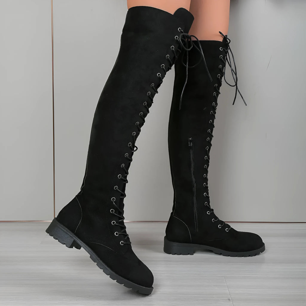 Black lace-up over-the-knee boots with round toe and flat rubber sole on a neutral background.