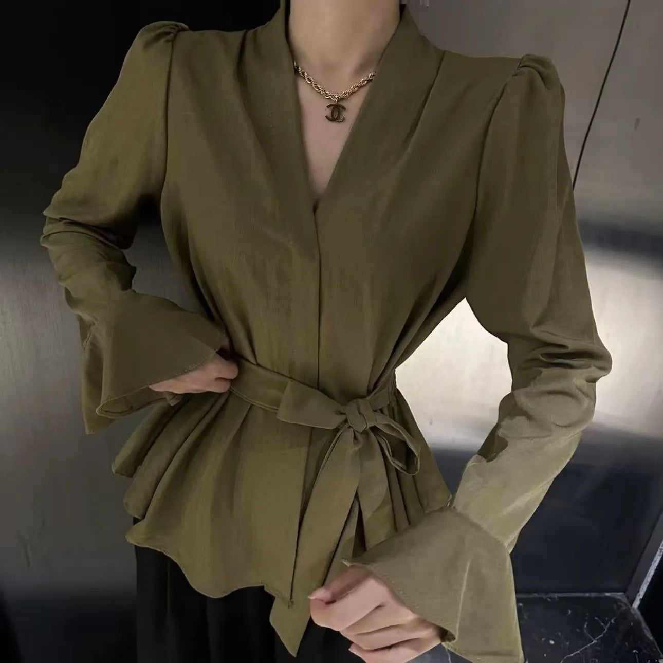 A woman's French-style black shirt with an irregular collar, long bell sleeves, and a tied front closure.