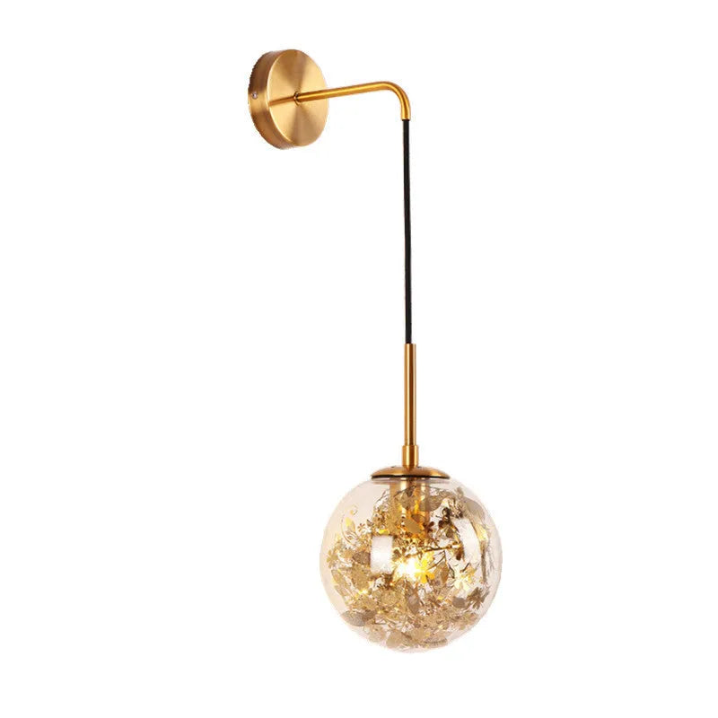 Modern glass wall lamp in golden flower finish mounted beside a bed.