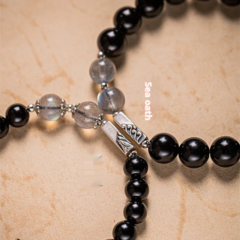 Black obsidian Buddha beads bracelets for couples, showing 8mm and 10mm bead sizes on a traditional cord.