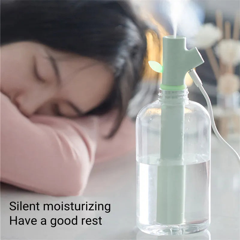 Transparent plastic branch-shaped USB portable air humidifier on a desk.