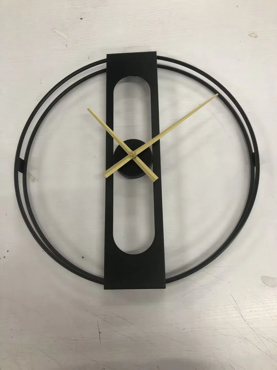Large 50cm round metal wall clock in black or gold colour on a wall.