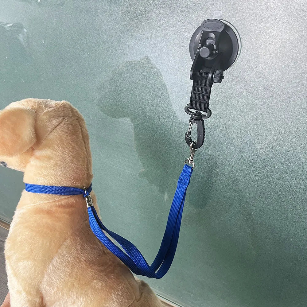 Black pet bathing restraint with four suction cups, a traction rope, and anti-bite handcuffs on a tiled wall.