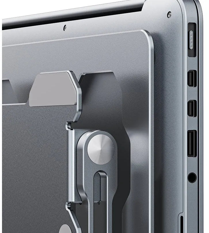 Grey aluminium adjustable laptop stand holding a silver laptop on a wooden desk.
