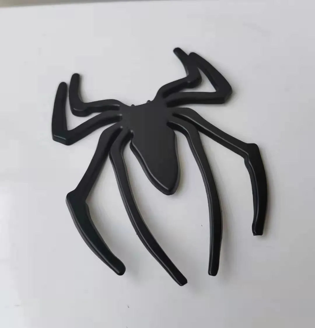 Three-dimensional metal spider bumper sticker in zinc alloy, showing gold, silver, black, and red colour options.
