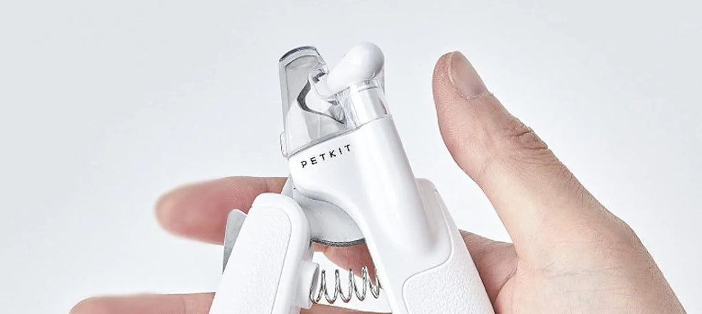 White pet nail clippers with LED light and transparent splash guard open, showing the triangular steel blade.