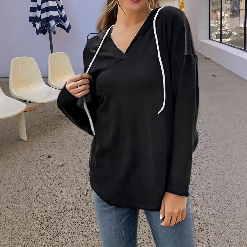 Women's red V-neck sweatshirt with hood and long sleeves showing loose fit design